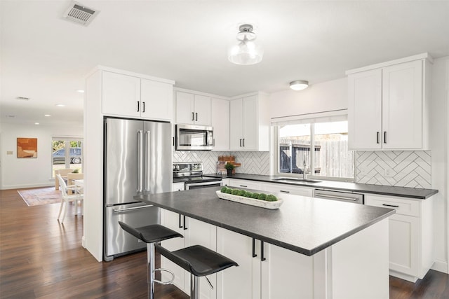 kitchen with backsplash, a center island, white cabinetry, and stainless steel appliances