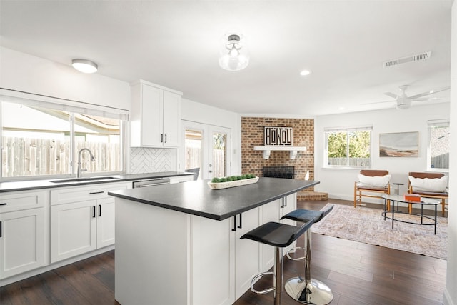 kitchen with white cabinets, tasteful backsplash, a kitchen island, and sink