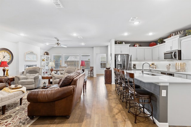 living room with ceiling fan, sink, and light hardwood / wood-style floors