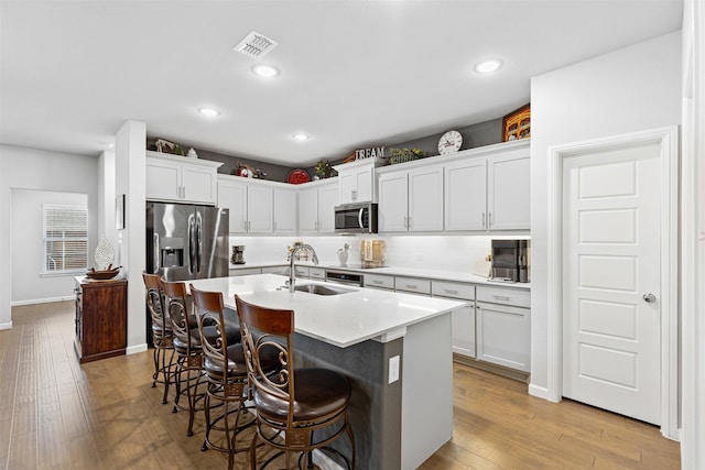 kitchen featuring white cabinetry, sink, a kitchen breakfast bar, an island with sink, and appliances with stainless steel finishes