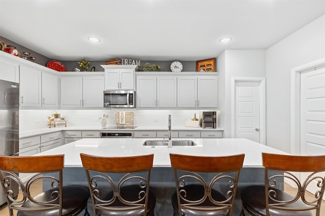 kitchen featuring a breakfast bar area, sink, stainless steel appliances, and a center island with sink