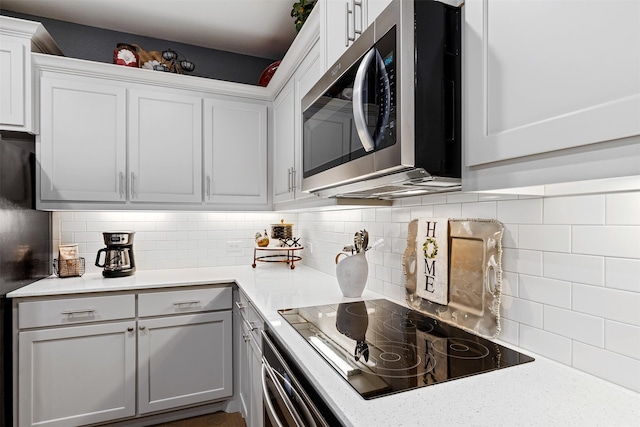 kitchen with white cabinetry, decorative backsplash, light stone countertops, and black appliances