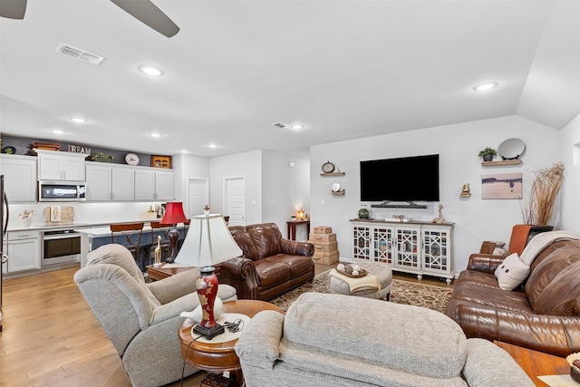 living room featuring ceiling fan, light hardwood / wood-style floors, and vaulted ceiling