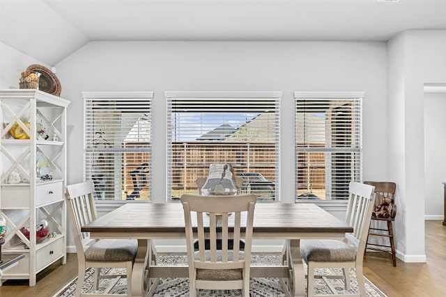 dining area featuring hardwood / wood-style flooring and vaulted ceiling