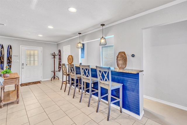 tiled dining area with a textured ceiling and ornamental molding