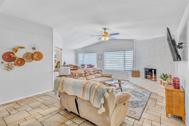 living room featuring ceiling fan, wood walls, lofted ceiling, and a brick fireplace