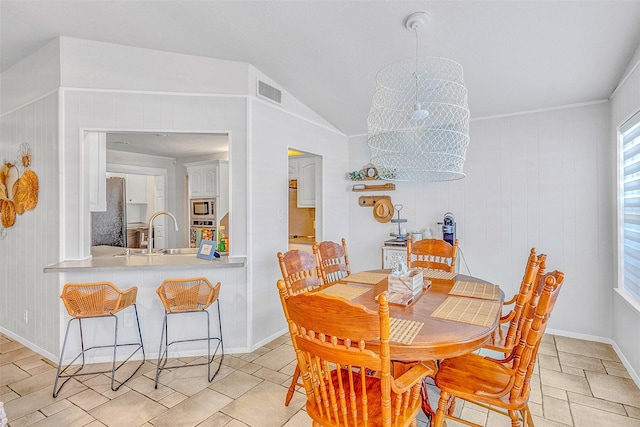 dining space featuring lofted ceiling, an inviting chandelier, wood walls, and sink