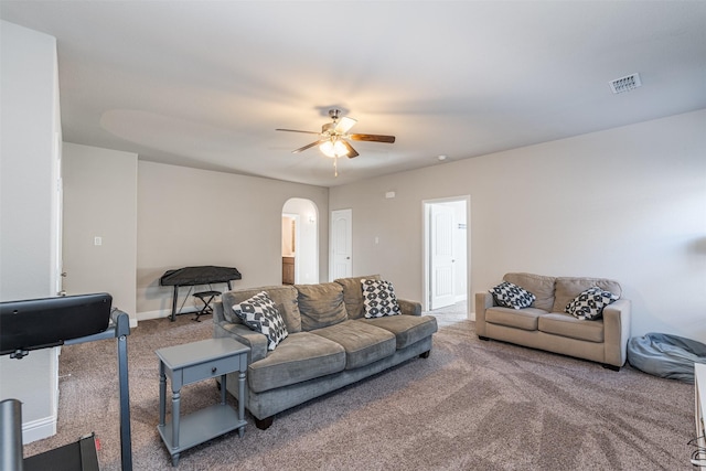 carpeted living area featuring a ceiling fan, arched walkways, visible vents, and baseboards