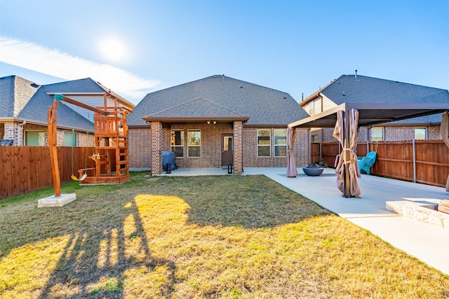 back of house with a patio area, a fenced backyard, a playground, and brick siding