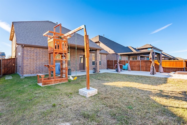 rear view of property featuring a patio area, brick siding, a yard, and a fenced backyard