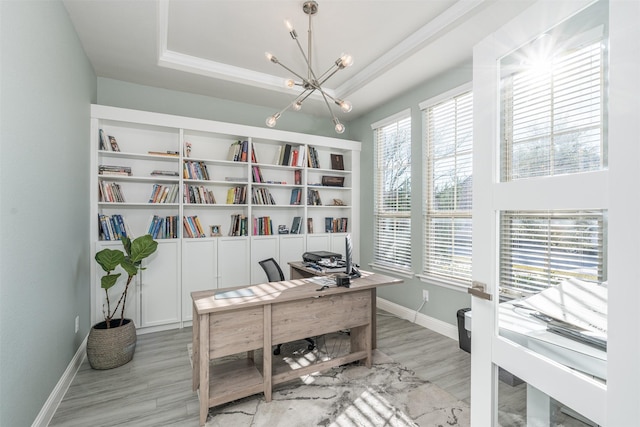 office featuring a raised ceiling, crown molding, light wood-type flooring, and a notable chandelier