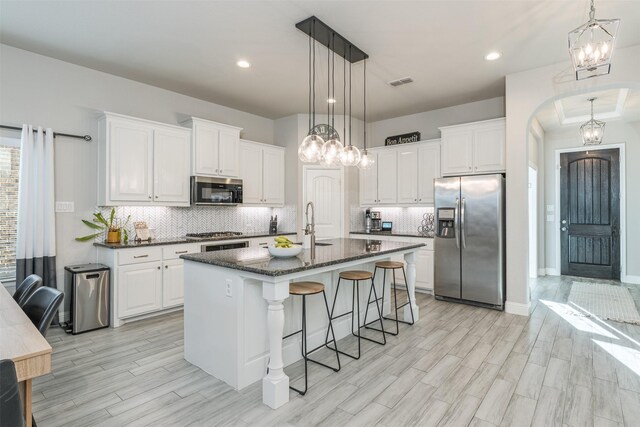 kitchen featuring an island with sink, stainless steel appliances, white cabinetry, and sink