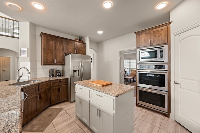 kitchen featuring sink, white cabinetry, tasteful backsplash, appliances with stainless steel finishes, and light stone countertops