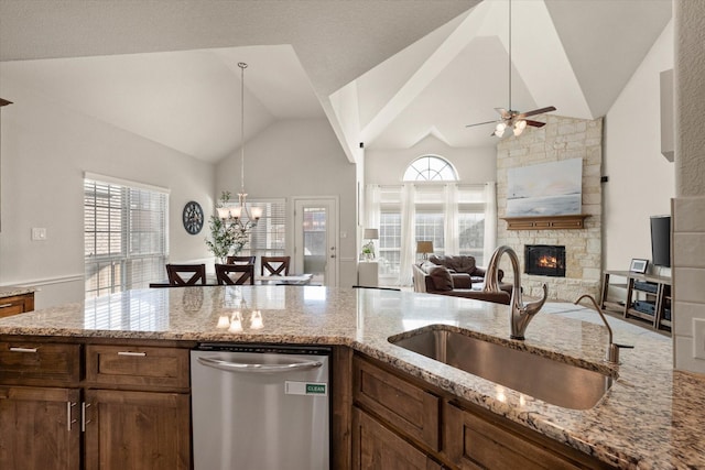 kitchen with dishwasher, light stone countertops, sink, and a fireplace