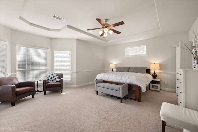 carpeted bedroom featuring ceiling fan and a raised ceiling