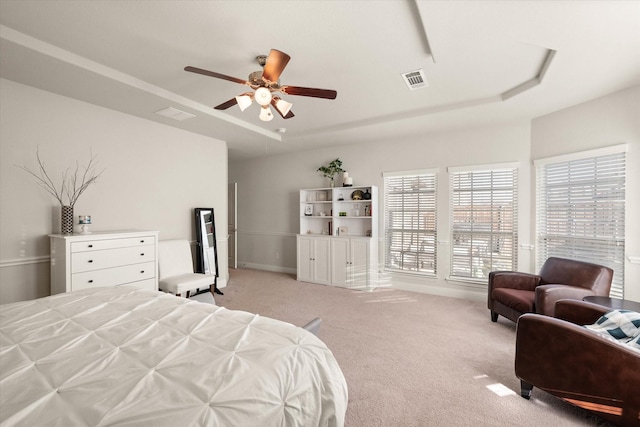 bedroom featuring ceiling fan, a tray ceiling, and multiple windows