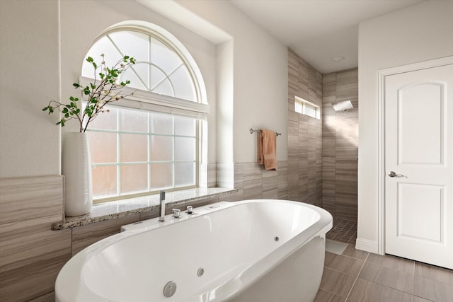 bathroom with a washtub, tile patterned floors, and tile walls