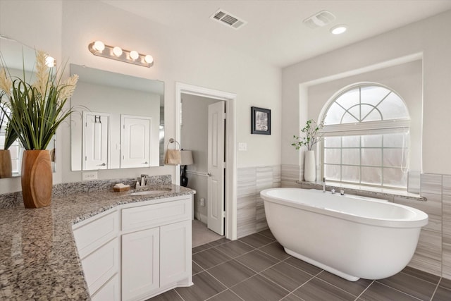 bathroom featuring a bathing tub, tile walls, vanity, and tile patterned floors