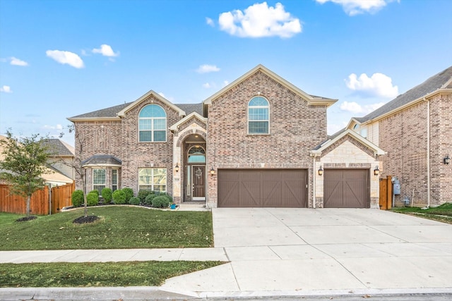 traditional-style house featuring brick siding, concrete driveway, an attached garage, a front yard, and fence