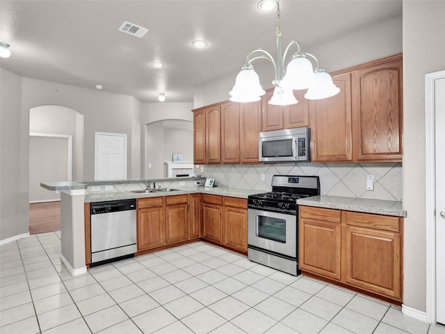 kitchen featuring appliances with stainless steel finishes, tasteful backsplash, sink, a chandelier, and light tile patterned floors