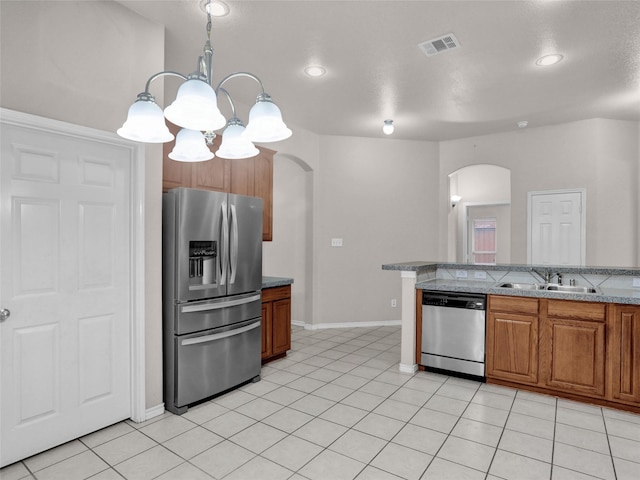 kitchen with appliances with stainless steel finishes, decorative light fixtures, sink, a notable chandelier, and light tile patterned flooring