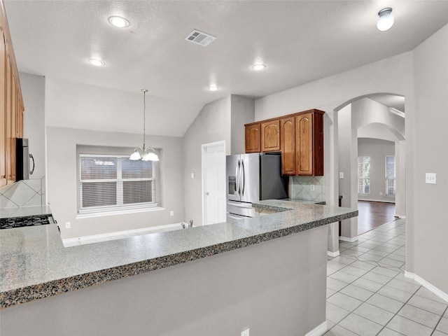 kitchen featuring pendant lighting, decorative backsplash, appliances with stainless steel finishes, light tile patterned floors, and a chandelier