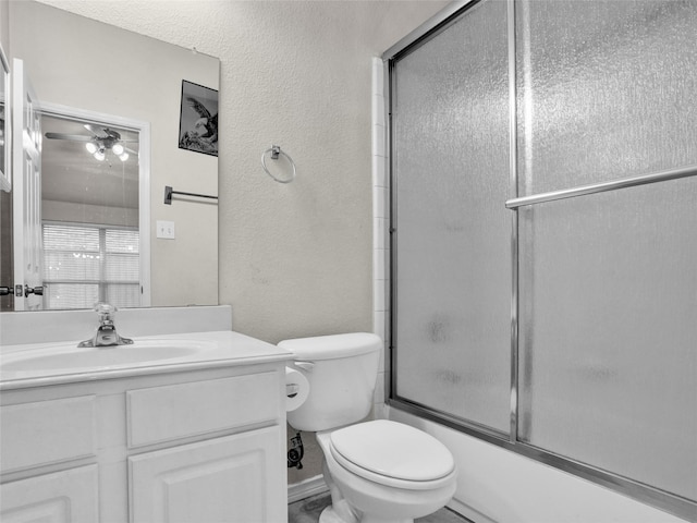 full bathroom with combined bath / shower with glass door, vanity, ceiling fan, and toilet