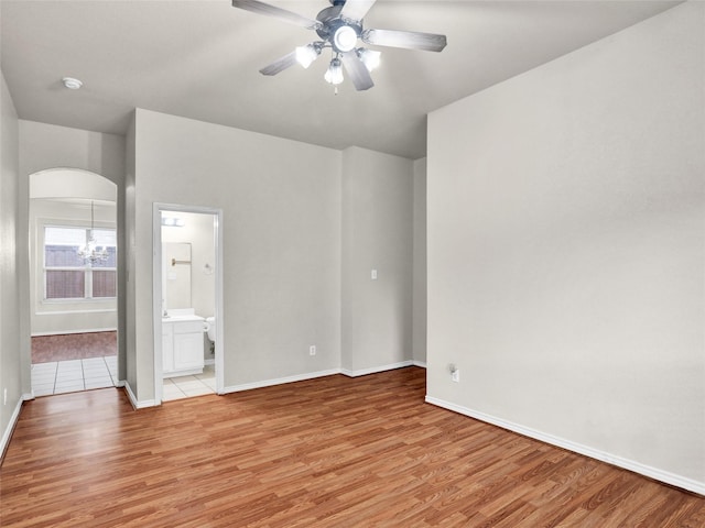 spare room featuring ceiling fan with notable chandelier and light hardwood / wood-style flooring