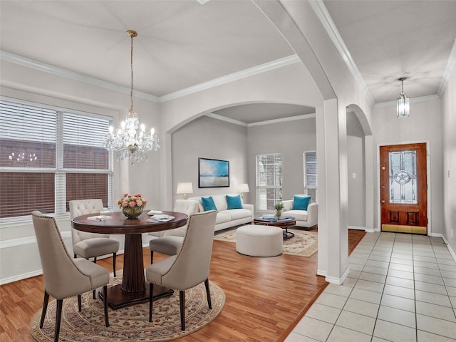 dining space with a healthy amount of sunlight, light tile patterned floors, ornamental molding, and an inviting chandelier