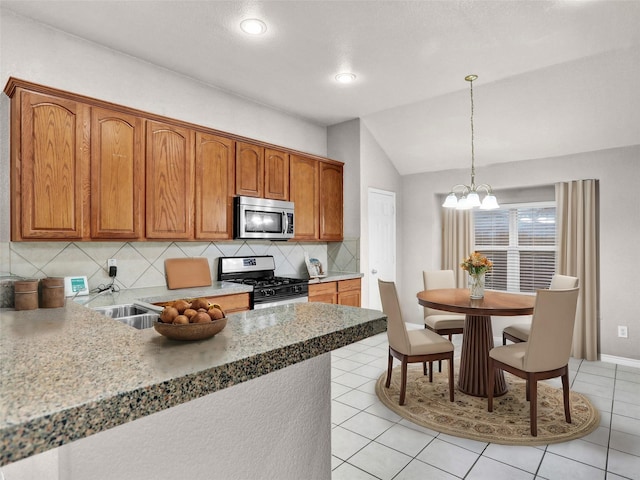 kitchen with lofted ceiling, decorative light fixtures, tasteful backsplash, appliances with stainless steel finishes, and a chandelier