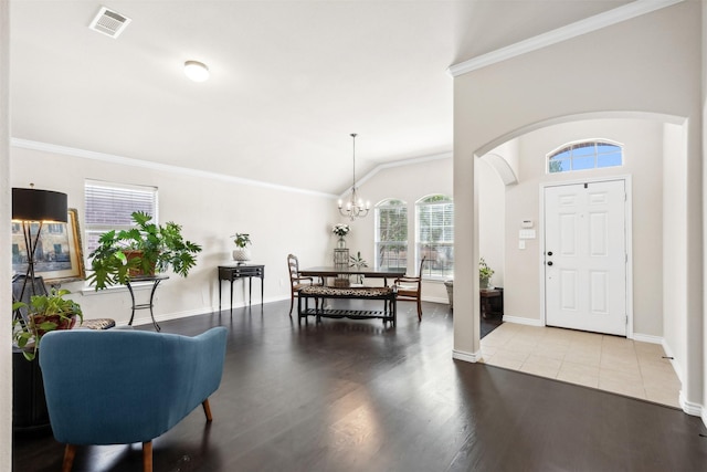 entrance foyer with an inviting chandelier, ornamental molding, light tile patterned floors, and vaulted ceiling