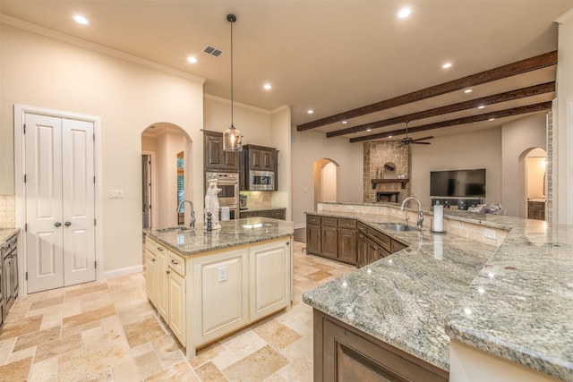 kitchen featuring light stone counters, a spacious island, sink, and hanging light fixtures