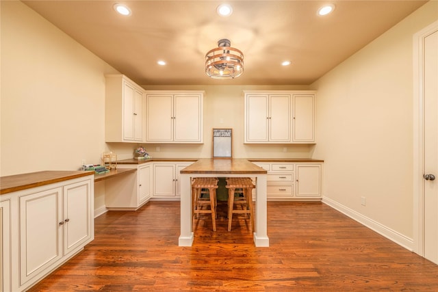 kitchen with white cabinetry, dark wood-type flooring, built in desk, and wood counters