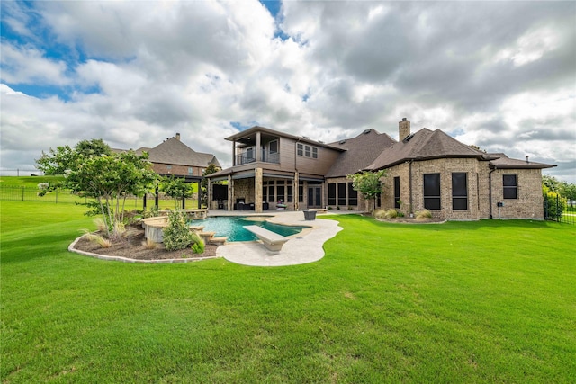 back of property with a balcony, a patio, and a lawn