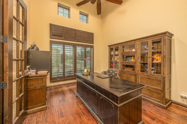 office with a high ceiling, ceiling fan, a healthy amount of sunlight, and dark hardwood / wood-style flooring