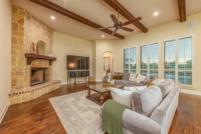 living room with dark hardwood / wood-style flooring, ceiling fan, a fireplace, and beamed ceiling