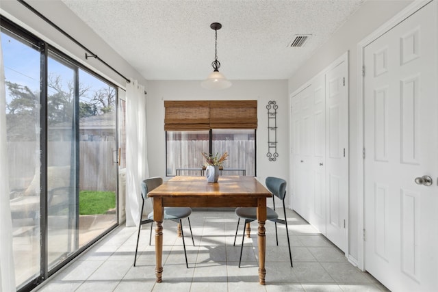 dining area featuring light tile patterned floors and a textured ceiling