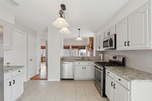 kitchen featuring pendant lighting, white cabinetry, sink, and appliances with stainless steel finishes