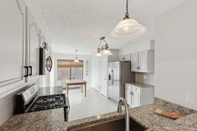 kitchen with sink, tasteful backsplash, pendant lighting, a textured ceiling, and appliances with stainless steel finishes