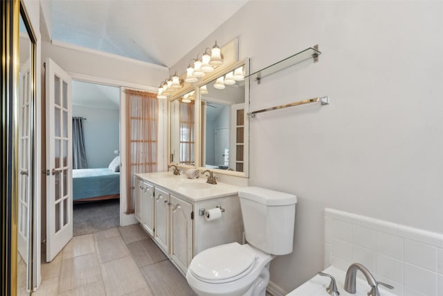 bathroom featuring toilet, french doors, vanity, and vaulted ceiling