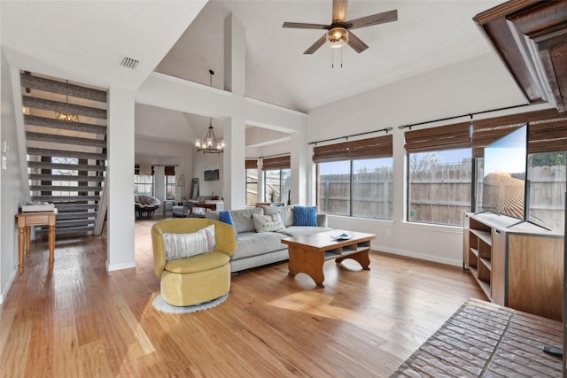 living room featuring high vaulted ceiling, light hardwood / wood-style floors, and ceiling fan with notable chandelier