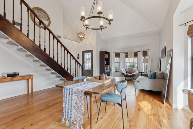 dining room featuring light wood-type flooring, high vaulted ceiling, and an inviting chandelier