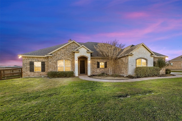 french country inspired facade featuring a yard