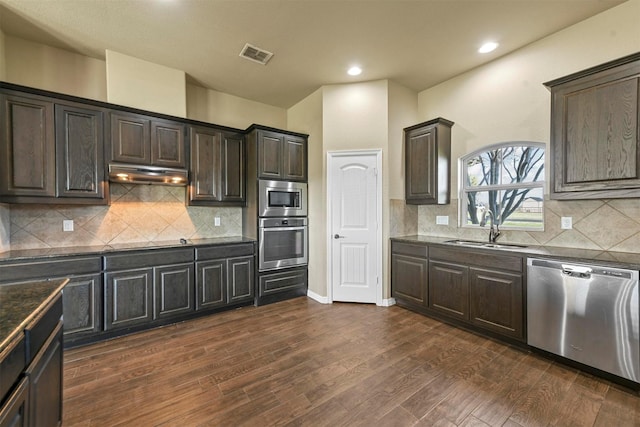 kitchen with sink, appliances with stainless steel finishes, tasteful backsplash, dark brown cabinets, and dark hardwood / wood-style flooring