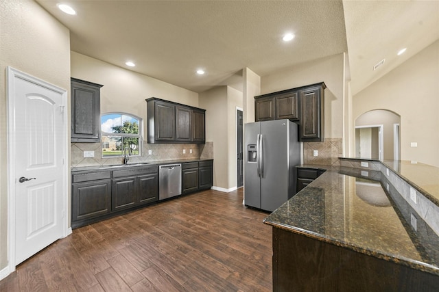 kitchen with decorative backsplash, stainless steel appliances, sink, dark stone countertops, and dark hardwood / wood-style floors