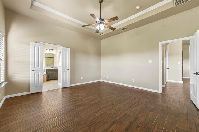 unfurnished room featuring ornamental molding, a raised ceiling, ceiling fan, hardwood / wood-style flooring, and a high ceiling