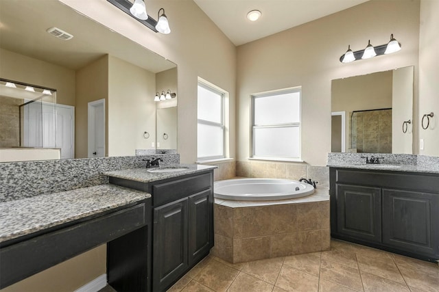 bathroom with vanity, a relaxing tiled tub, and tile patterned floors