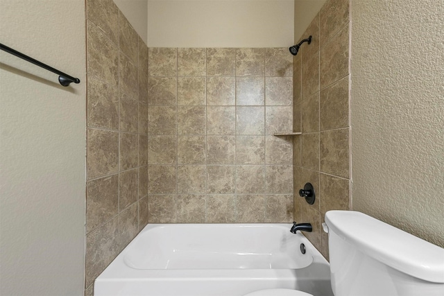 bathroom featuring tiled shower / bath combo and toilet