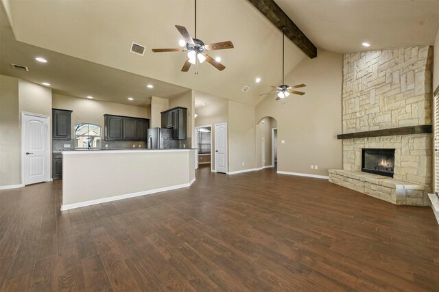 unfurnished living room with beamed ceiling, dark hardwood / wood-style flooring, and a stone fireplace