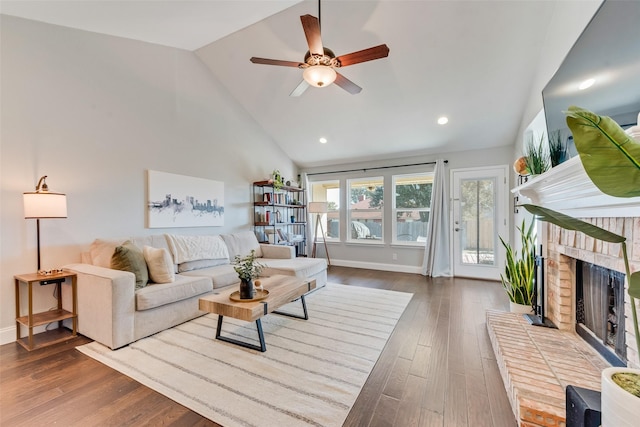 living room with high vaulted ceiling, hardwood / wood-style flooring, a brick fireplace, and ceiling fan